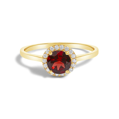 Close-up front angle of a yellow metal ring featuring a round red gemstone in a four-prong setting, surrounded by a circle of small round white gemstones in a shared prong setting.
