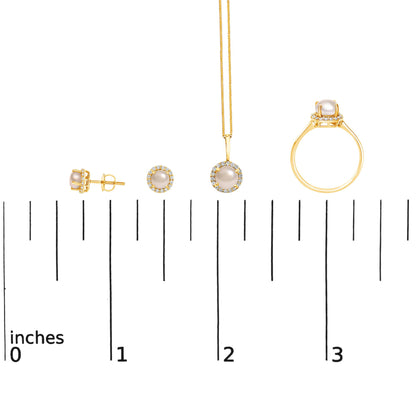 Set of yellow metal jewelry including round stud earrings, a pendant on a thin chain, and a ring, all featuring central white pearls surrounded by white round gemstones in shared prong settings, shown from a side and front angle on a measuring scale.