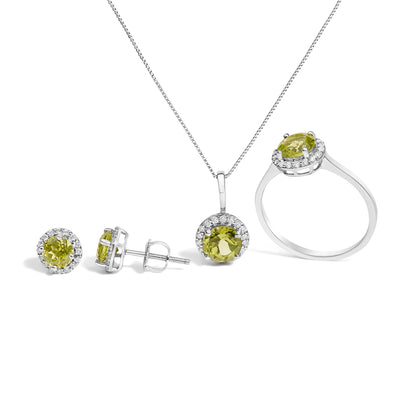 Front and side view of a white metal jewelry set including a ring, pendant necklace, and pair of stud earrings, each featuring a round green gemstone surrounded by small round white gemstones, shown against a white background.