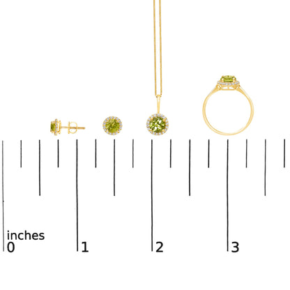 Jewelry set shown on a scale, consisting of yellow metal earrings, a pendant necklace, and a ring, each featuring a round green gemstone surrounded by small round white gemstones in shared prong settings, shown from front and side angles.