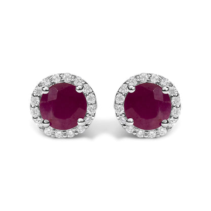Close-up front view of a pair of round stud earrings featuring a central red gemstone surrounded by a halo of small white gemstones in shared prong settings.