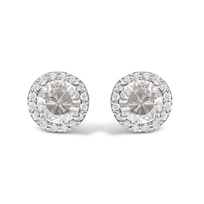 Close-up front view of a pair of round stud earrings featuring a central white round gemstone surrounded by a halo of small white round gemstones in shared prong settings. The earrings have a white metal color.