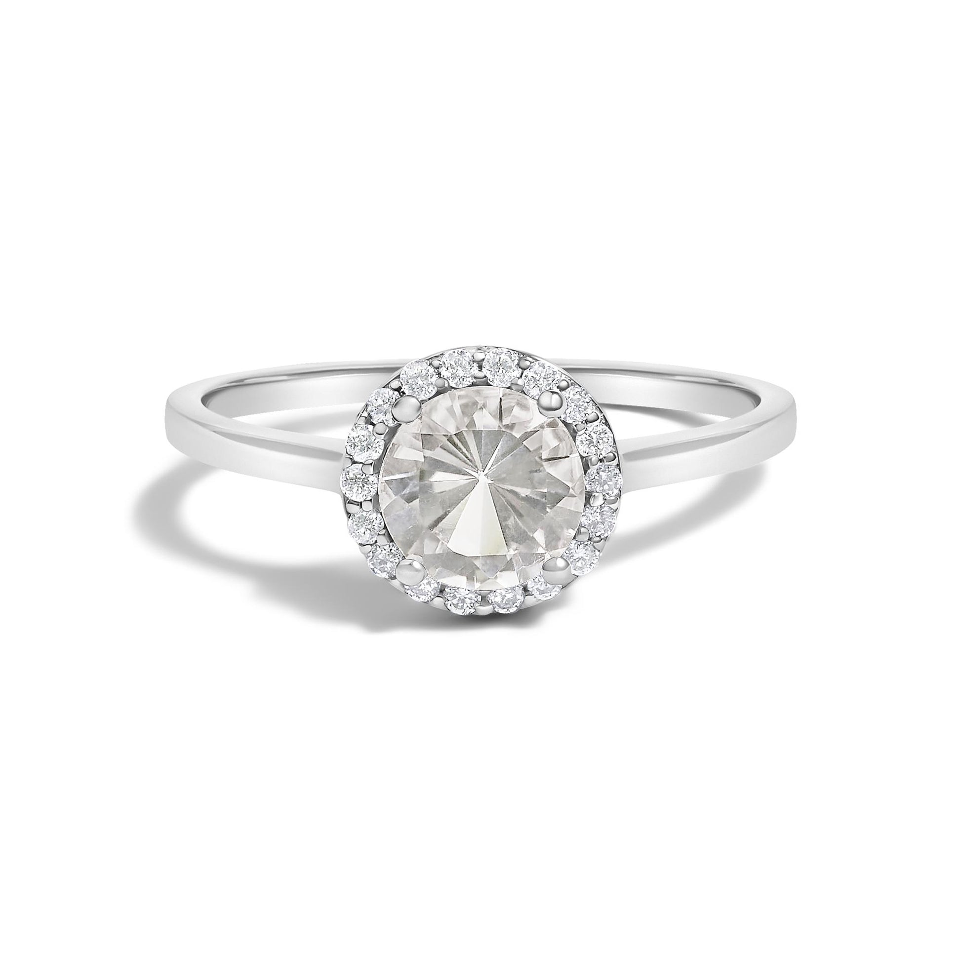 Close-up front view of a white metal ring featuring a central round white gemstone surrounded by a circle of small round white gemstones in a shared prong setting, shown on a white background.