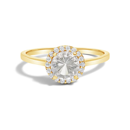 Front view of a yellow metal ring with a large round white gemstone center surrounded by a halo of small round white gemstones in a shared prong setting.